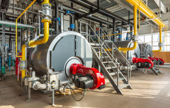 The interior of an industrial boiler room with three large boile