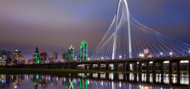 image of a bridge over a river at night time - buildings with green lights