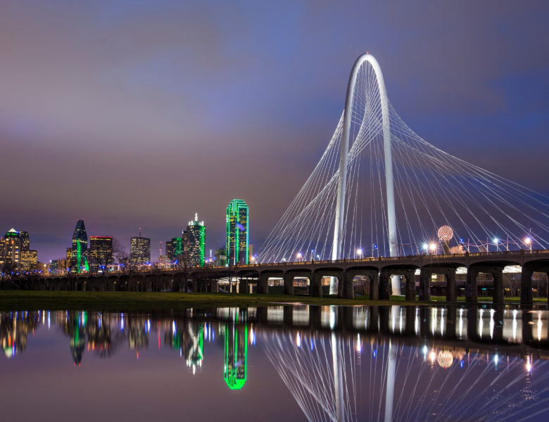 image of a bridge over a river at night time - buildings with green lights